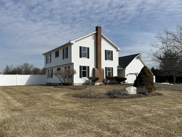 rear view of property featuring a yard, fence, and a chimney