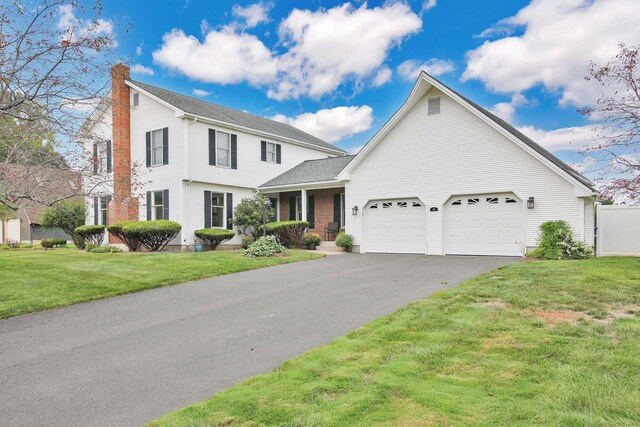 view of front of house with a garage, a chimney, a front lawn, and aphalt driveway