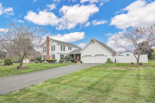 view of front of property featuring a chimney, a front yard, fence, a garage, and driveway