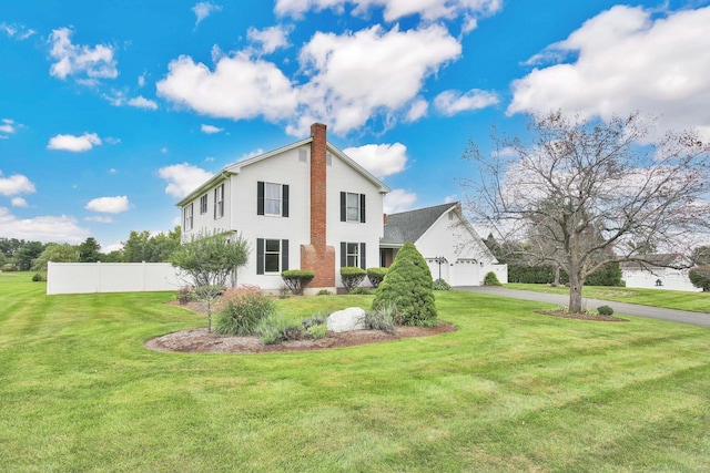 view of side of property featuring aphalt driveway, a garage, fence, a yard, and a chimney