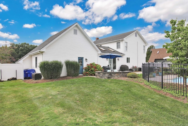 rear view of property featuring fence, a lawn, and a patio