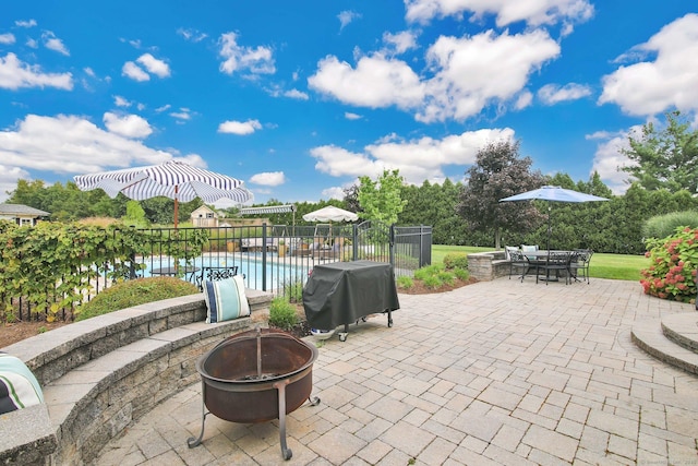 view of patio / terrace featuring a fire pit, fence, grilling area, a fenced in pool, and outdoor dining space