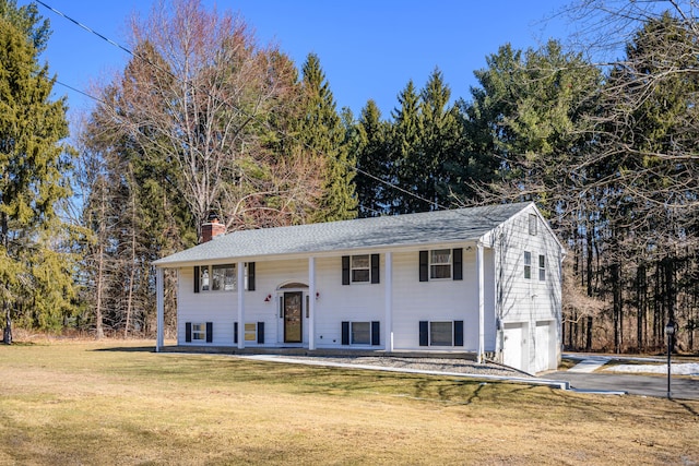 bi-level home with driveway, an attached garage, a chimney, and a front lawn