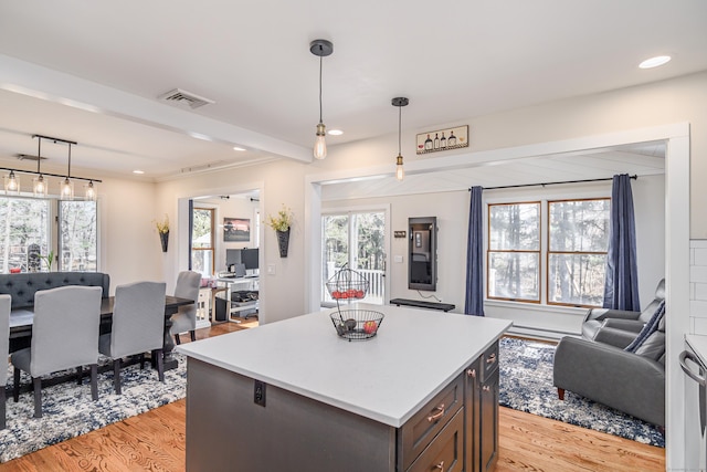 kitchen featuring light wood-style flooring, a kitchen island, open floor plan, light countertops, and hanging light fixtures