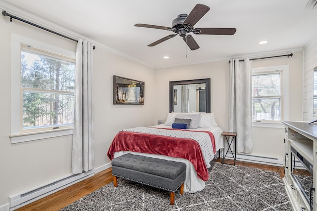 bedroom with a baseboard heating unit, ornamental molding, and wood finished floors