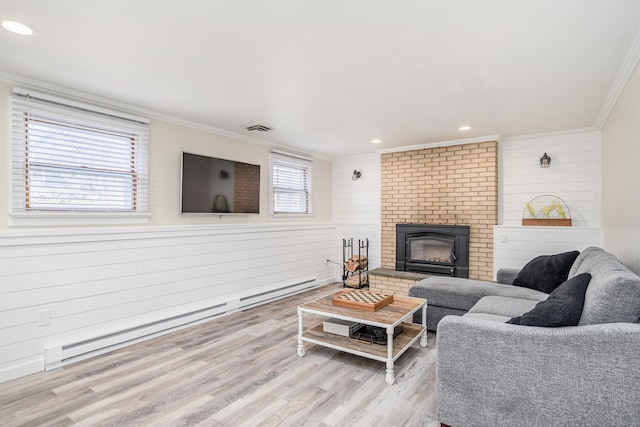 living area featuring visible vents, wood finished floors, crown molding, a fireplace, and a baseboard heating unit