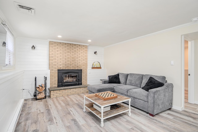 living room featuring baseboards, visible vents, wood finished floors, crown molding, and a brick fireplace