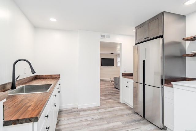 kitchen with visible vents, wood counters, freestanding refrigerator, open shelves, and a sink