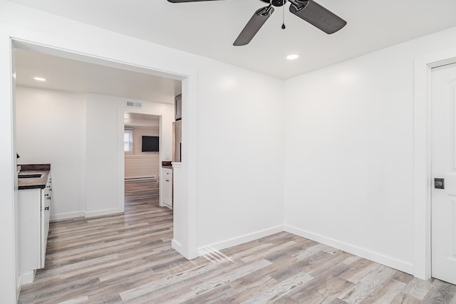 spare room featuring a baseboard radiator, baseboards, light wood finished floors, and recessed lighting