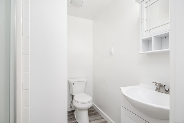 bathroom featuring vanity, wood finished floors, toilet, and baseboards