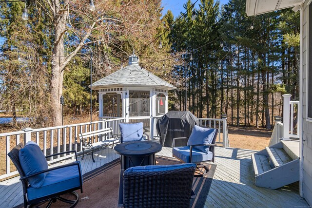 wooden terrace with a gazebo, area for grilling, and an outdoor living space with a fire pit