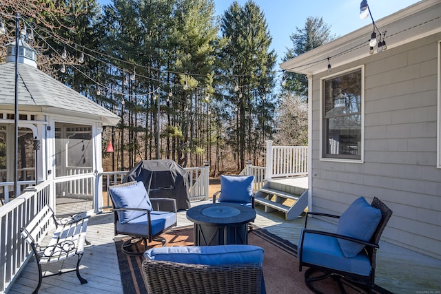 deck with an outdoor fire pit, area for grilling, and a sunroom