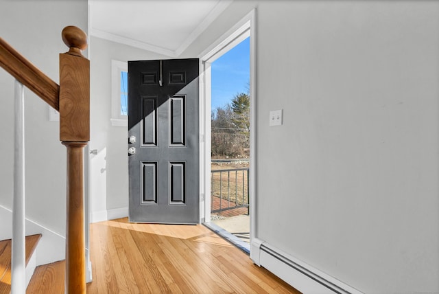 entrance foyer featuring light wood finished floors, baseboards, stairway, baseboard heating, and crown molding