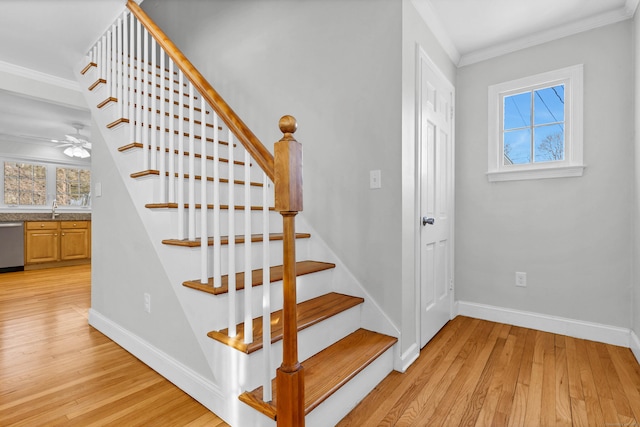 staircase with ornamental molding, a healthy amount of sunlight, baseboards, and wood finished floors