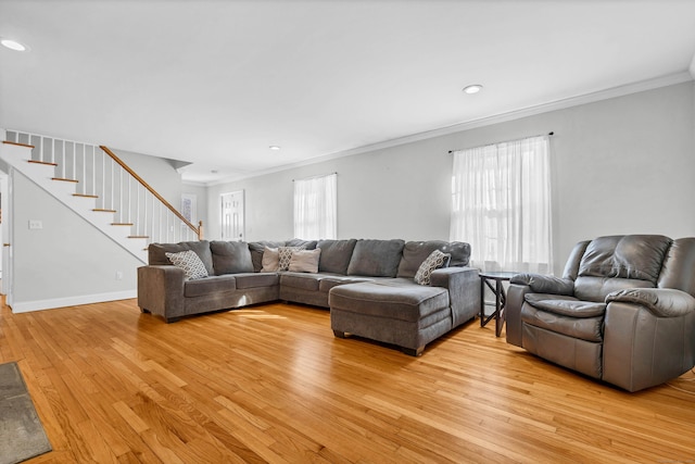 living room with ornamental molding, a healthy amount of sunlight, light wood-style flooring, and stairs