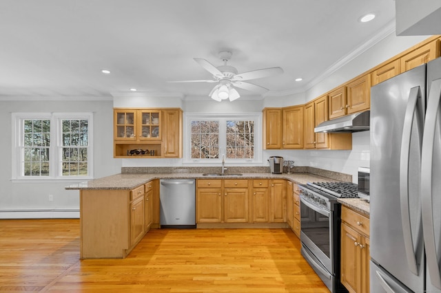 kitchen with appliances with stainless steel finishes, a baseboard heating unit, a sink, a peninsula, and under cabinet range hood