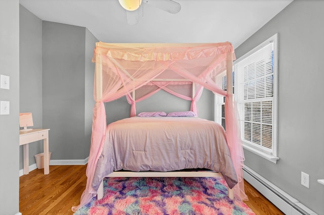 bedroom featuring a ceiling fan, a baseboard radiator, baseboards, and wood finished floors