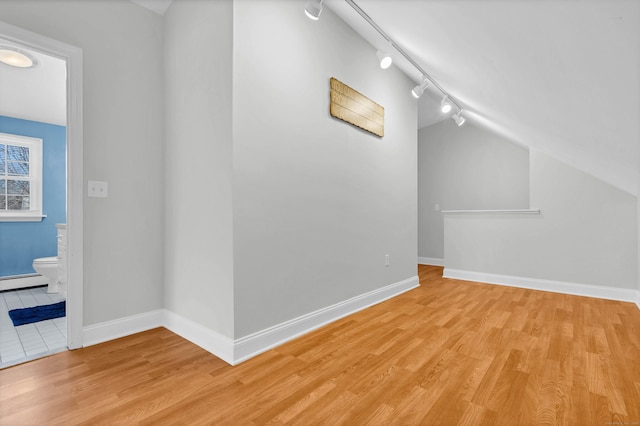 additional living space with lofted ceiling, baseboard heating, wood finished floors, and baseboards