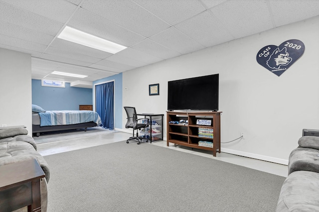 living area with a drop ceiling and baseboards