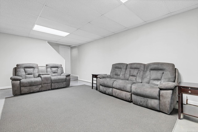 living area with a drop ceiling and baseboards