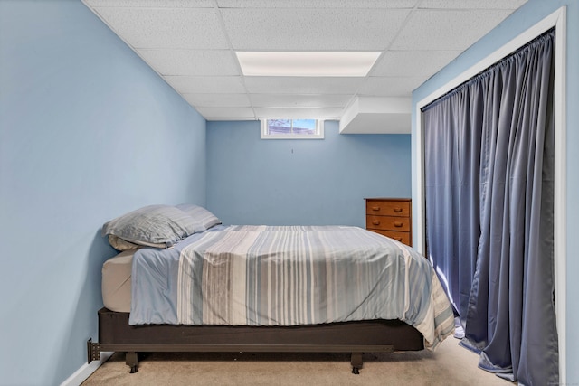 carpeted bedroom with a drop ceiling and baseboards