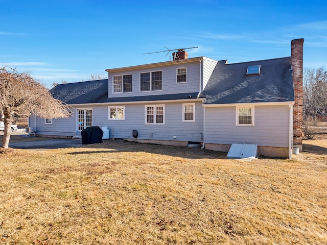 rear view of property featuring a shingled roof, a chimney, and a lawn