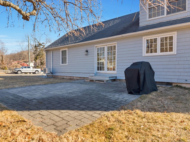 rear view of house featuring a shingled roof and a patio