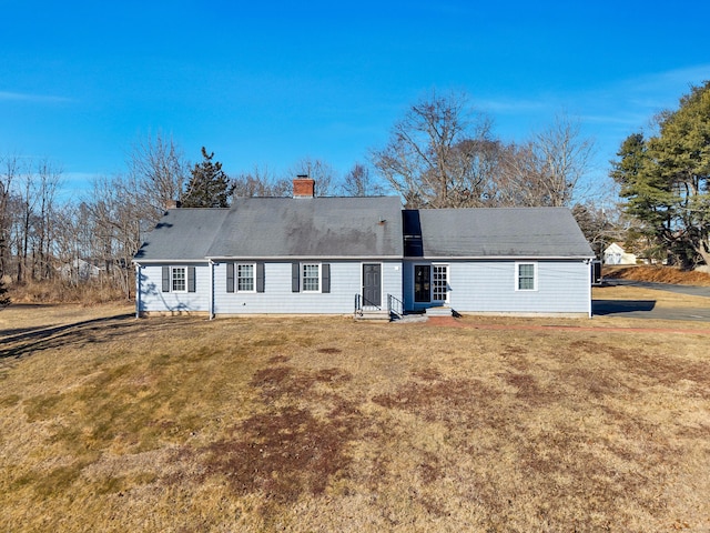 rear view of house featuring a chimney and a lawn