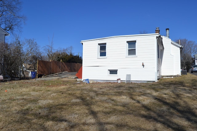 view of property exterior featuring a chimney, fence, and central AC