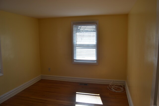 spare room with visible vents, baseboards, and wood finished floors