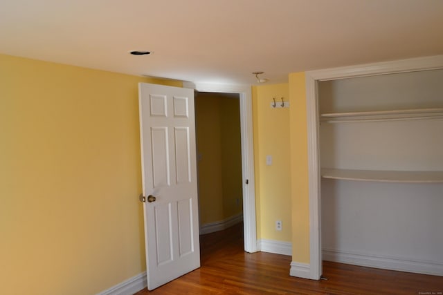 unfurnished bedroom featuring a closet, baseboards, and wood finished floors