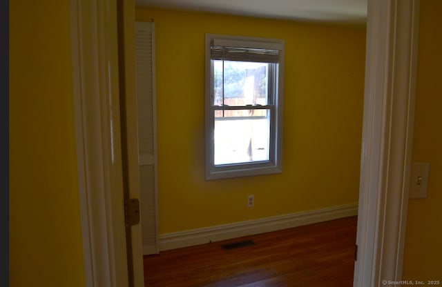 empty room featuring visible vents, dark wood finished floors, and baseboards