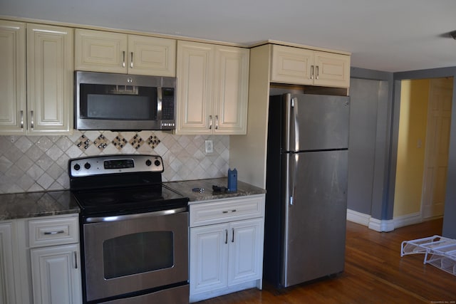 kitchen featuring appliances with stainless steel finishes, dark wood-style flooring, backsplash, and dark stone countertops