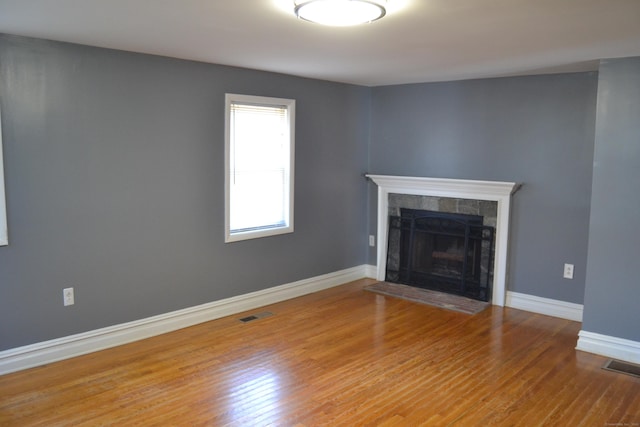 unfurnished living room featuring visible vents, a fireplace, baseboards, and wood finished floors