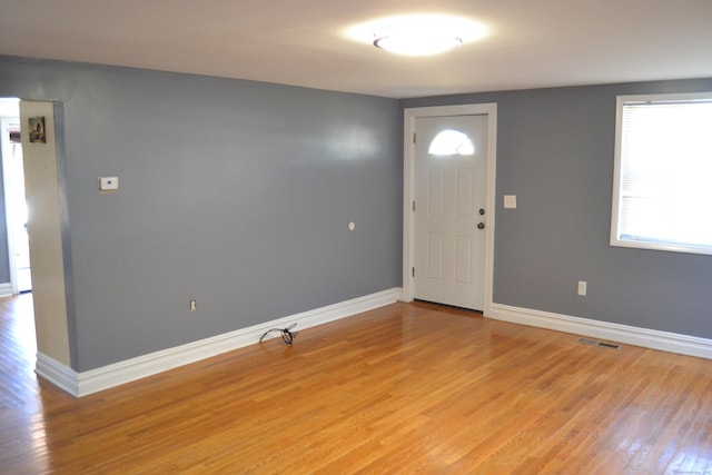 foyer entrance with visible vents, light wood-style flooring, and baseboards