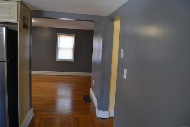 hallway with visible vents, baseboards, and wood finished floors