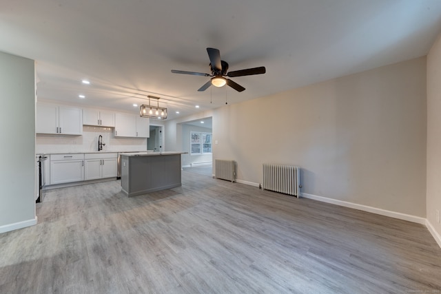 kitchen featuring radiator heating unit, a kitchen island, white cabinetry, and a sink