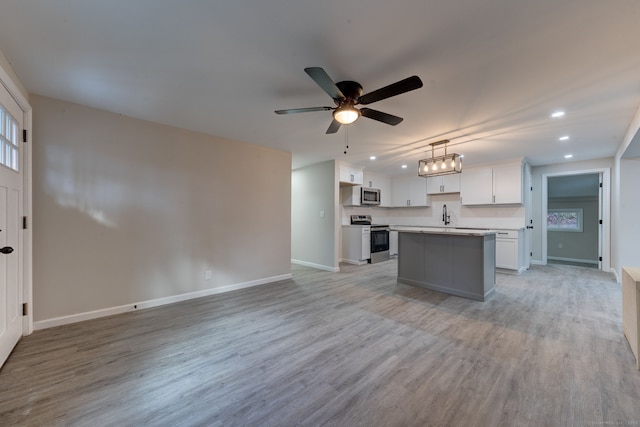 kitchen with stainless steel appliances, light wood-style flooring, open floor plan, white cabinetry, and a kitchen island