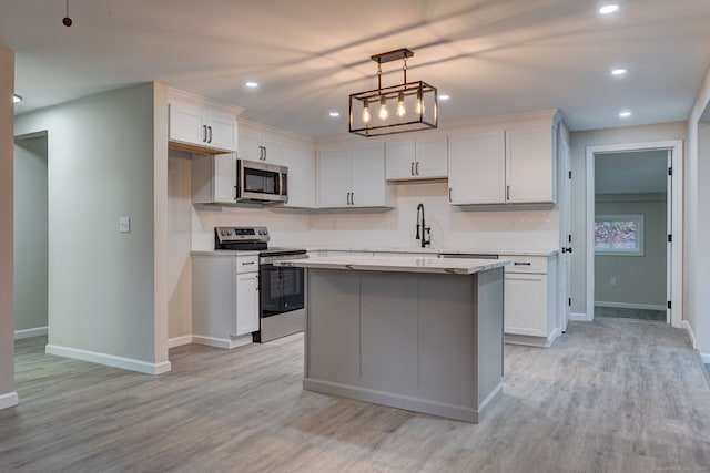 kitchen with appliances with stainless steel finishes, light wood-type flooring, backsplash, and a center island