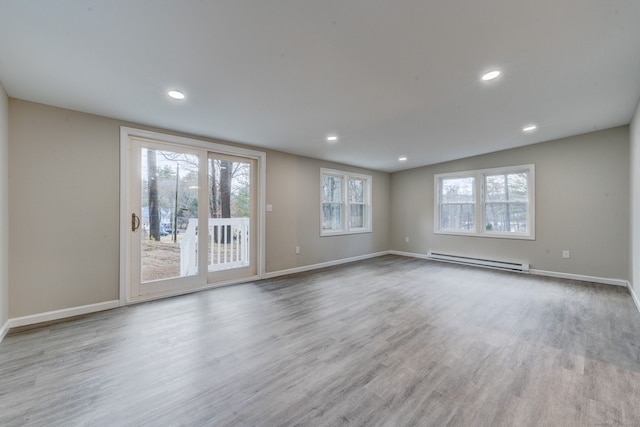 unfurnished room featuring baseboard heating, recessed lighting, wood finished floors, and baseboards