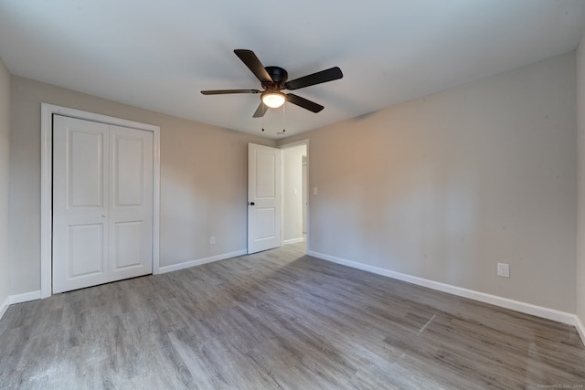 unfurnished bedroom featuring a ceiling fan, a closet, baseboards, and wood finished floors