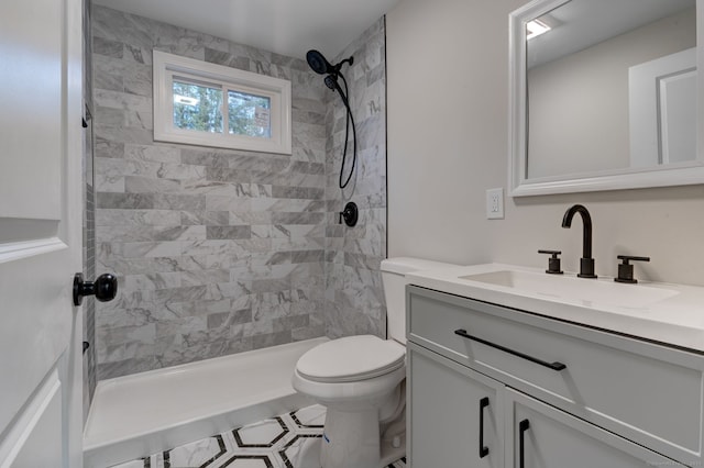 full bathroom with a tile shower, vanity, and toilet