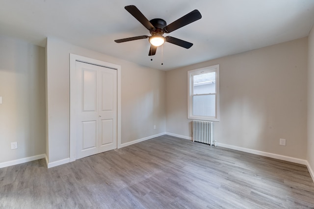 unfurnished bedroom with baseboards, wood finished floors, and radiator