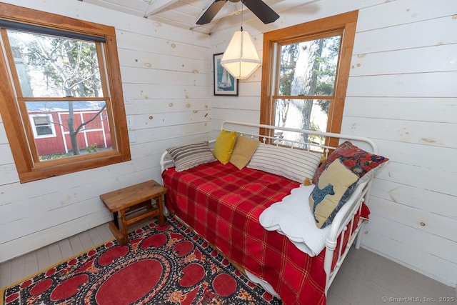 sitting room featuring wooden walls and a ceiling fan