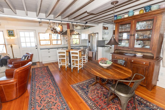 dining room with beam ceiling and wood finished floors