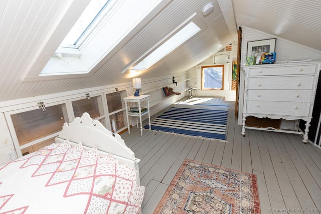 bedroom featuring lofted ceiling with skylight, wood walls, and wood-type flooring