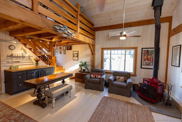 living area featuring a wood stove, wooden walls, light wood-style floors, wood ceiling, and vaulted ceiling with beams