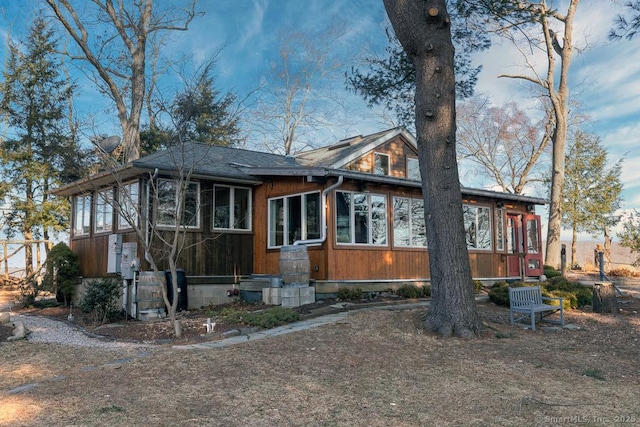 view of front of house with a shingled roof and a sunroom