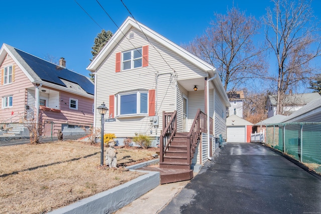 view of front of home featuring an outbuilding, driveway, a detached garage, and fence