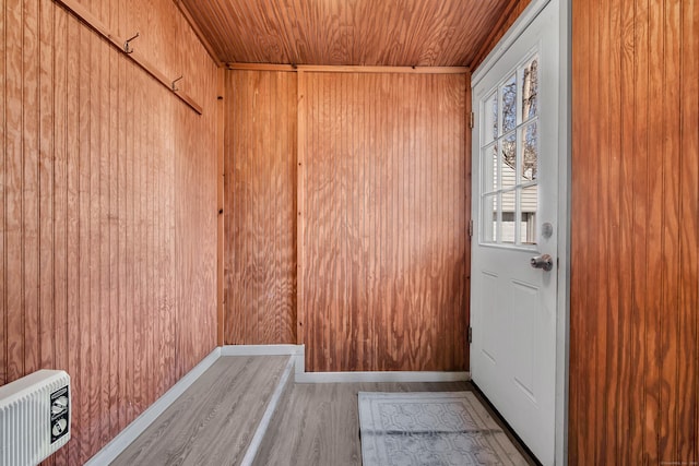 doorway with wood ceiling, wood walls, baseboards, and wood finished floors